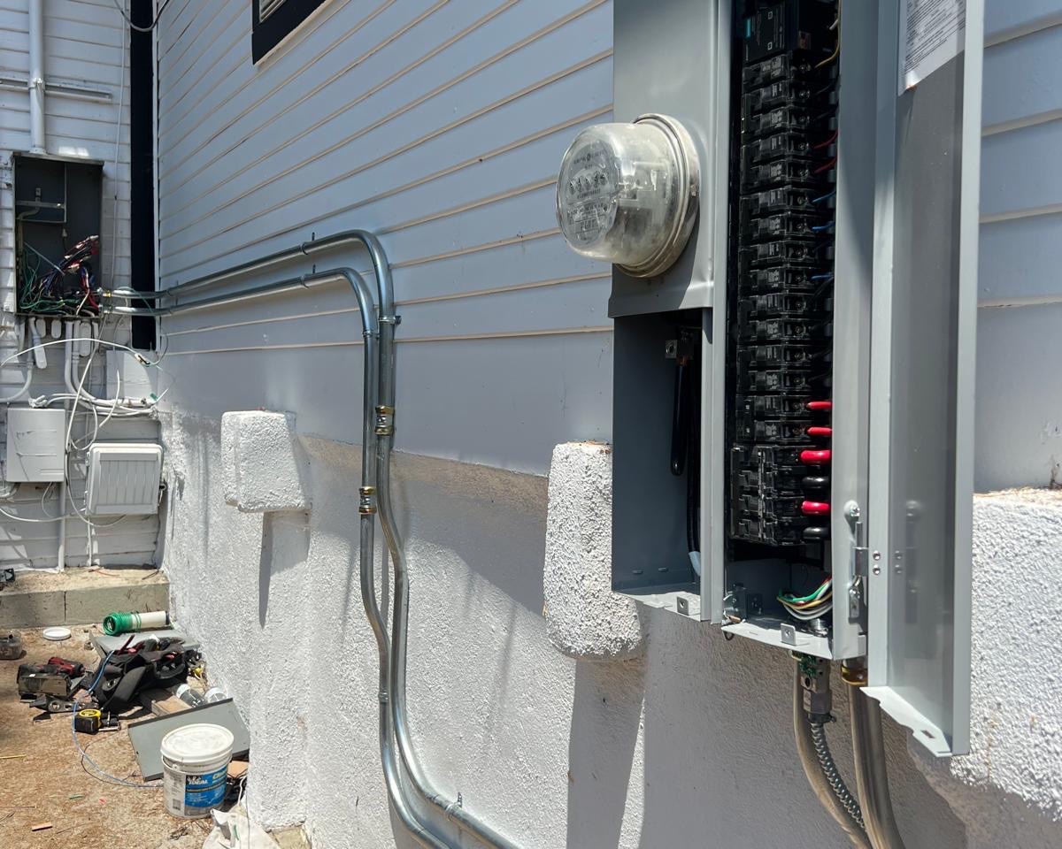 Electrical panel and meter upgrade completed by A+ Electric & Plumbing in Los Angeles: new circuit breaker panel with fresh conduit on a home exterior.